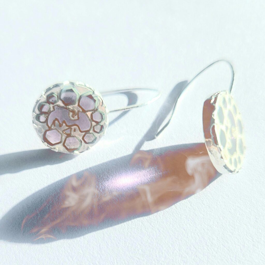 small pink face earrings reflecting light